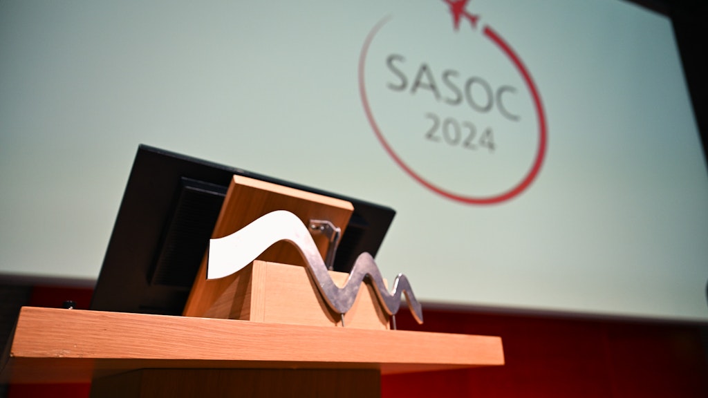 Ein Rednerpult und dahinter eine Leinwand. Darauf ist das Logo der Swiss Aviation Safety and Operations Conference (SASOC) 2024 zu sehen.