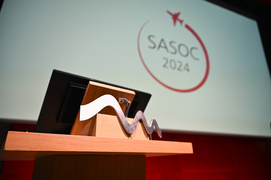 Ein Rednerpult und dahinter eine Leinwand. Darauf ist das Logo der Swiss Aviation Safety and Operations Conference (SASOC) 2024 zu sehen.